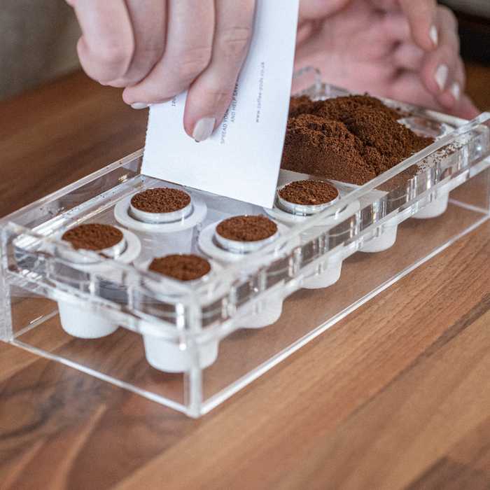Lady filling coffee pods with ground coffee beans