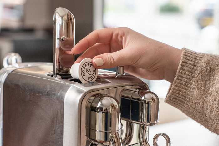 Lady placing a coffee pod into a coffee machine